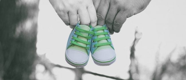 Parent Employee Rights | Parental Leave | Close up of a couple's hands carrying a pair of baby shoes